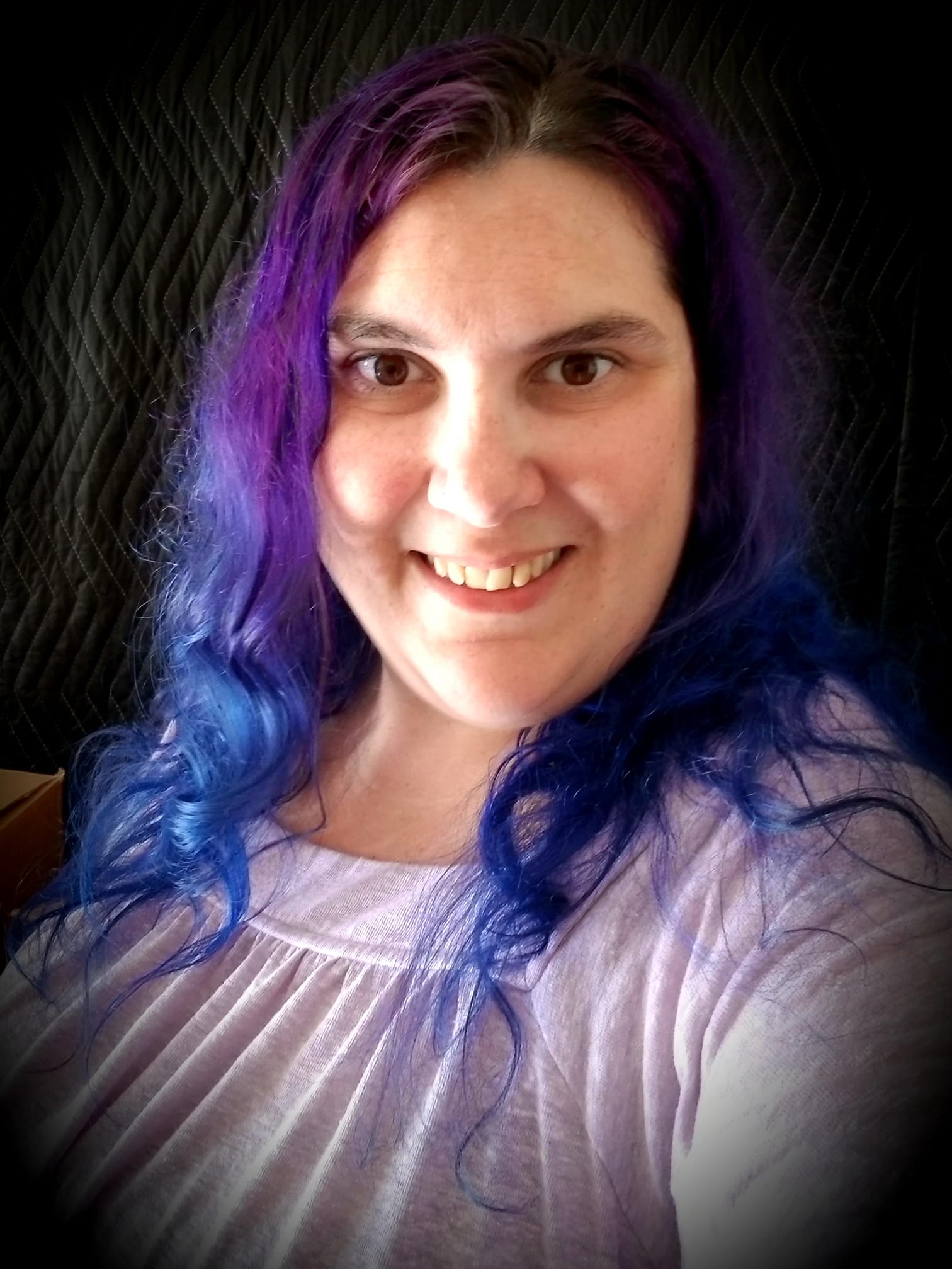 Dr. T smiling with long wavy purple and blue hair